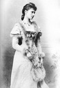 1892 Princess Alexandra standing wearing a fur-trimmed dress and holding a fur-trimmed fan