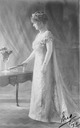 ca. 1911 Margaret Evelyn Cambridge standing in left side profile and holding a fan in her right hand. She wears the Mary Adelaide of Teck diamond crescent tiara From www.pinterest.com/katmaxoz/20th-century-fashion-in-photos